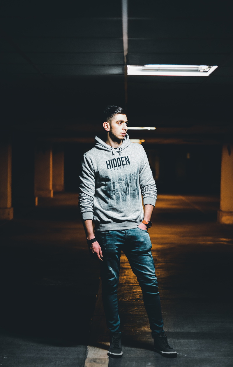 real people, sweater, apparel, looking, contemplation, clothing, indoors, footwear, built structure, text, t-shirt, teenager, column, one person, window