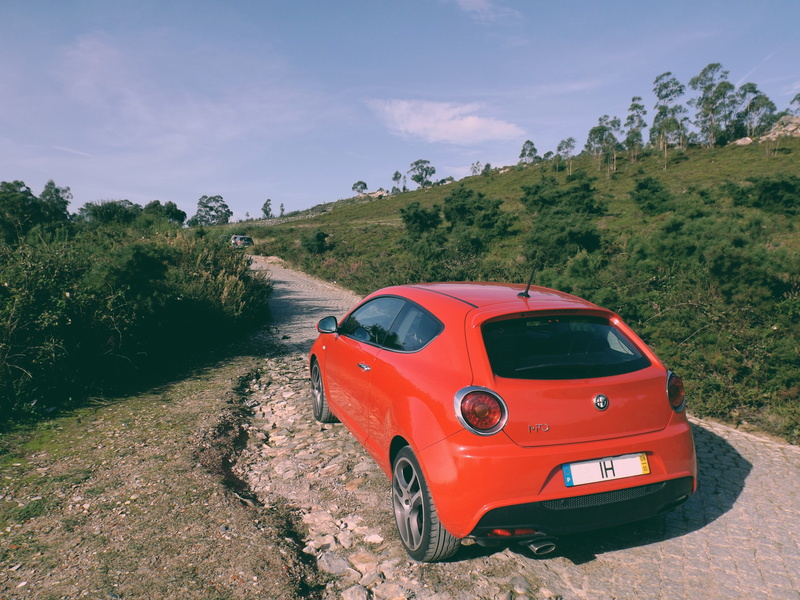 outdoors, road, motor vehicle, MiTo, plant, land vehicle, sky, non-urban scene, no people, green color, red, beauty in nature, mode of transportation, mountain