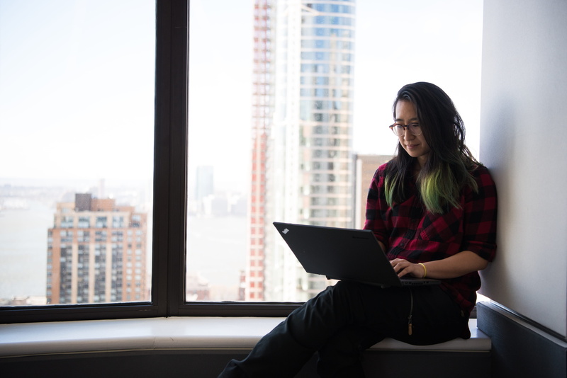 red, outdoors, wearing, facial expression, indoors, laptop, beautiful woman, elbow, young women, work, building exterior, eyeglasses, one person, working