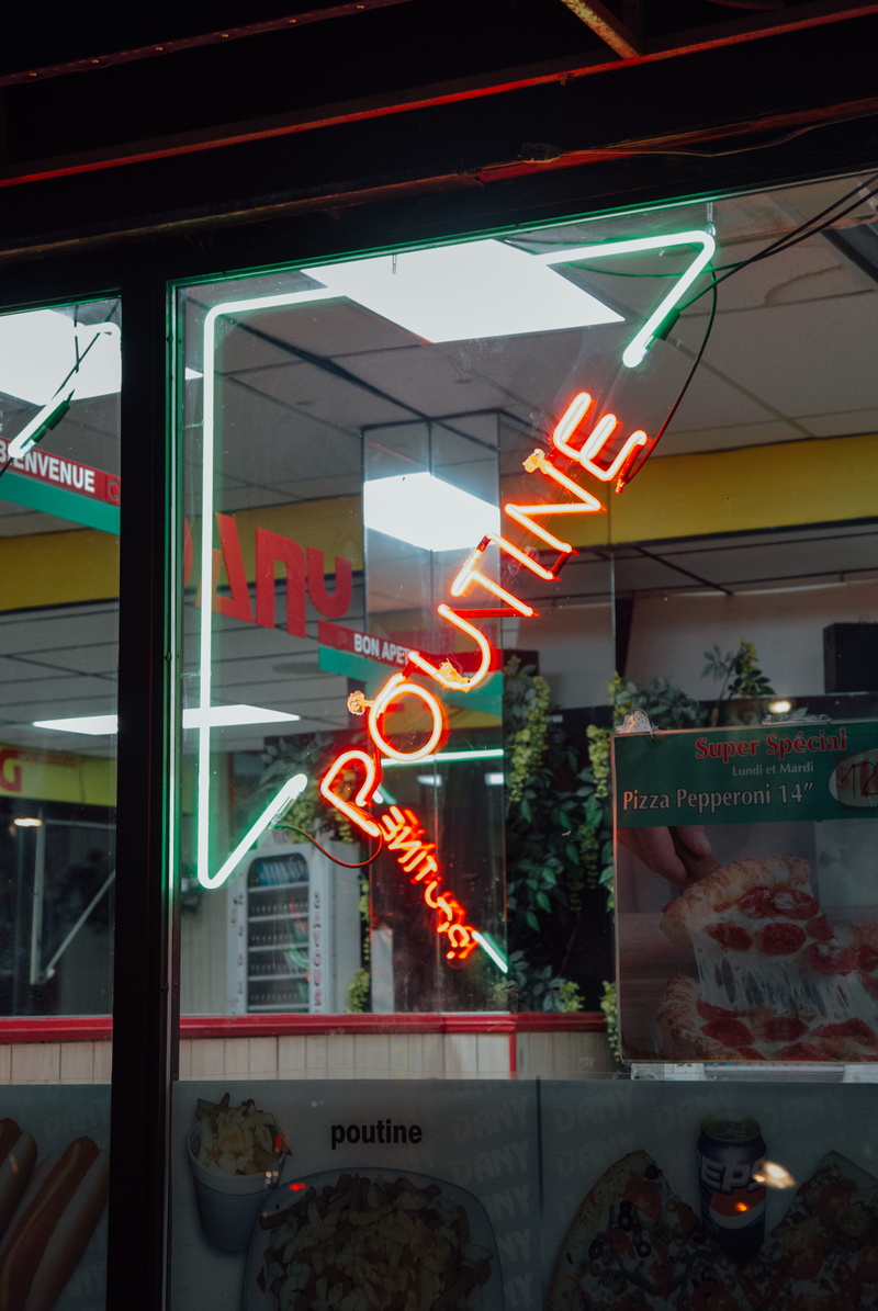 text, glass - material, signage, business, no people, sign, poutine, built structure, illuminated, glowing, outdoors, architecture, transparent, green