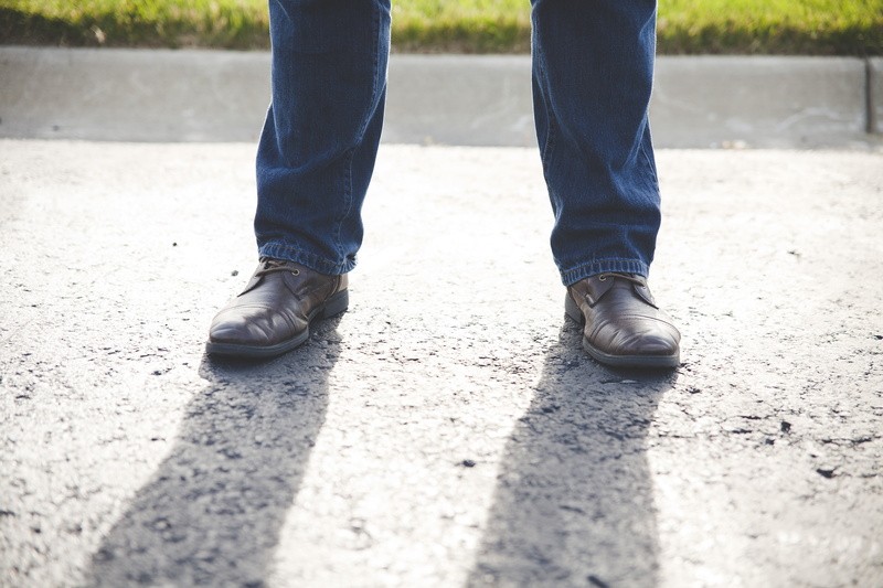 casual clothing, shoe, shadow, surface level, city, men, wear, standing, nature, man, grass, human limb, adult, sunlight, body part, focus, blur, day, human leg