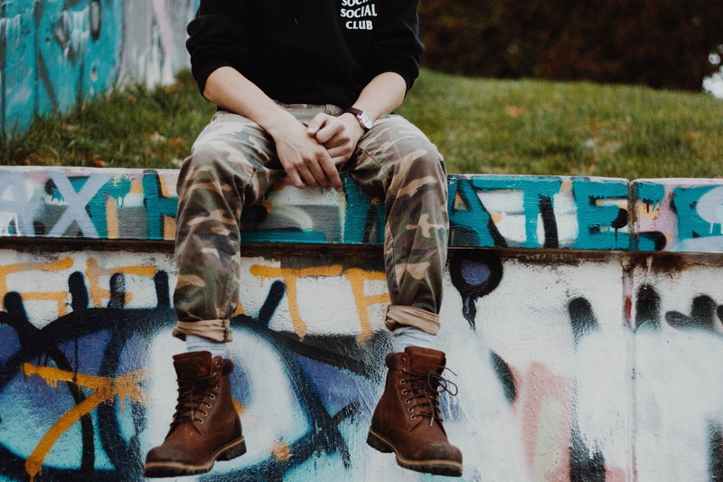 outdoors, women, lifestyles, sits, leather, people, work, graffiti, guy, city, sitting, pants, front view, human Leg, boots, casual clothing, urban Scene