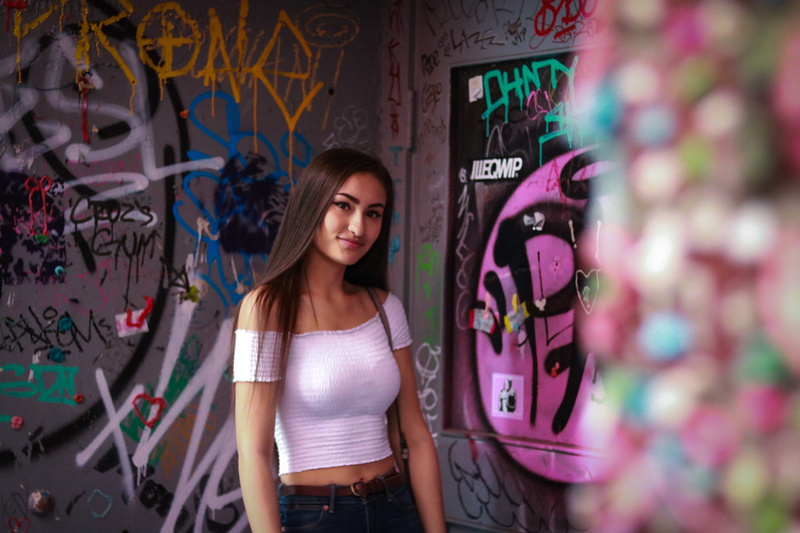 pike place market, wall - building feature, confidence, gumwall, white shirt, long hair, young women, graffiti, front view, teenager, young adult, 5K