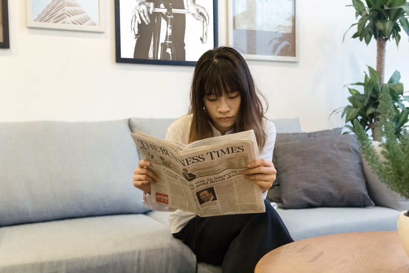 front view, domestic room, young adult, newspaper, indoors, three quarter length, furniture, holding, lady, house, asia girl, casual clothing, news paper