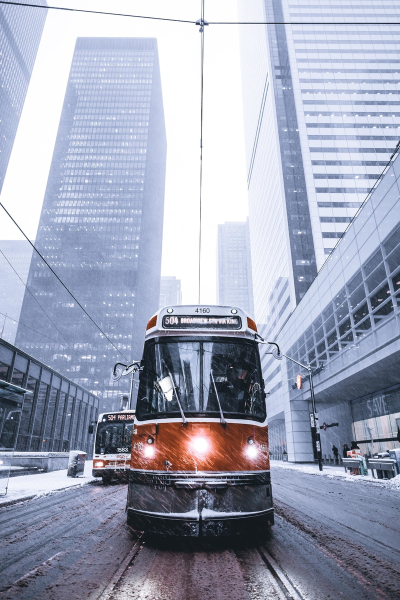 vehicle, bus, buildings, office building exterior, motor vehicle, city, tram lines, downtown district, business, car, downtown, city street, cityscape