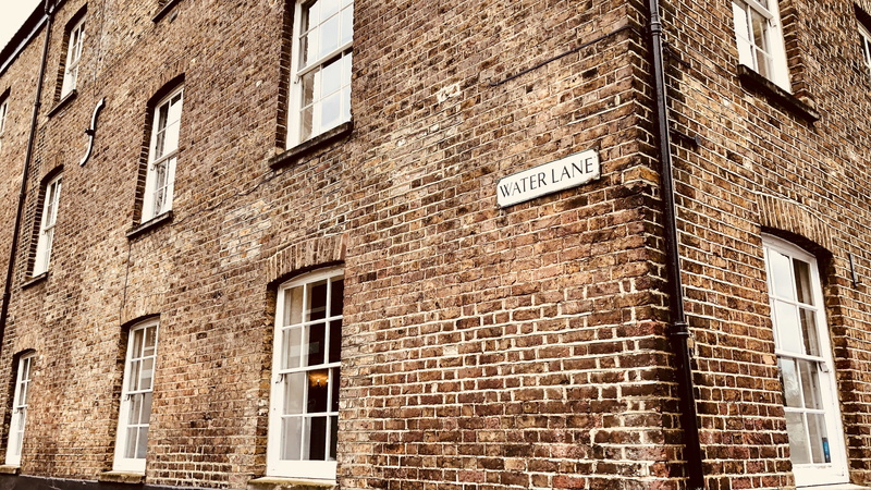 low angle view, sign, no people, architecture, day, western script, wall - building feature, brick wall, building exterior, text, full frame, arrow symbol