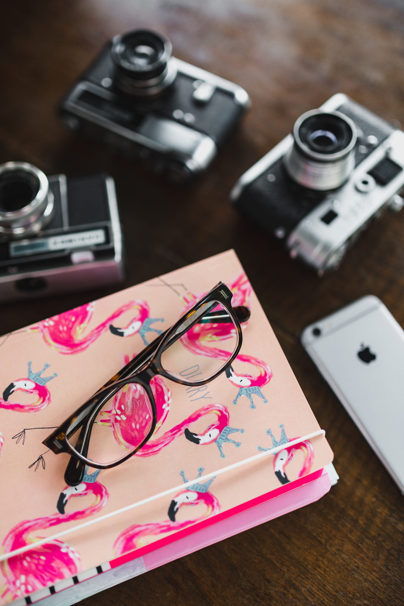 glasses, lens - optical instrument, high angle view, wood - material, photographic equipment, connection, focus on foreground, wireless technology, camera - photographic equipment
