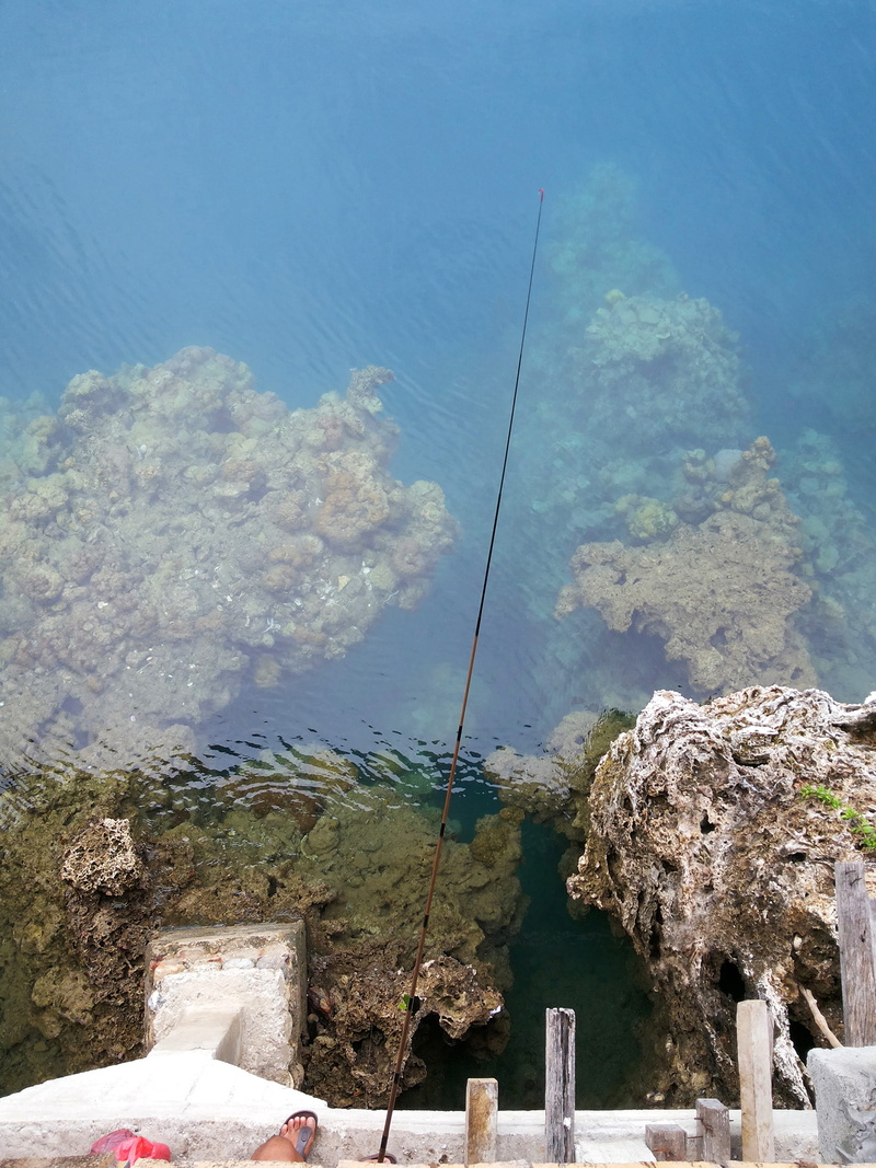 rock, fishing, built structure, bening, solid, tranquil scene, rock - object, outdoors, water, blue, beauty in nature, turquoise colored, 2K, sea, nature