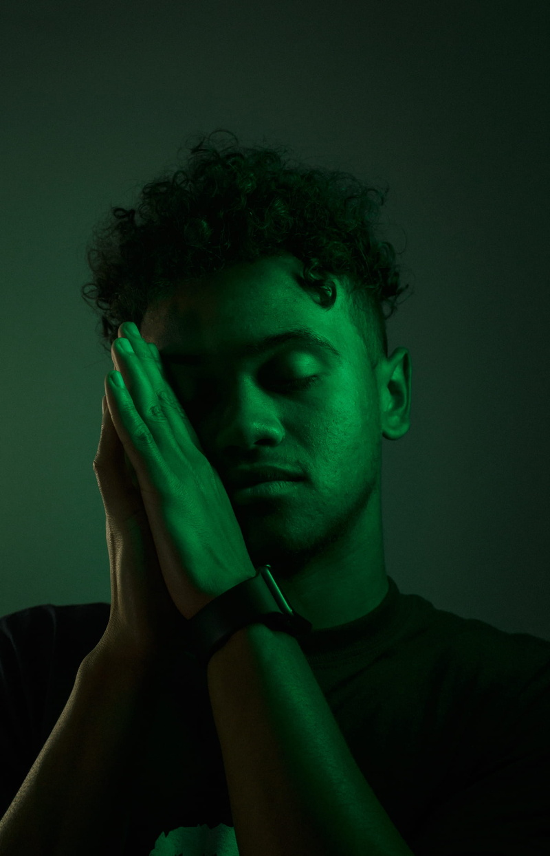 front view, black background, gobo, human hand, margate, dark, green, young adult, teenage boys, portrait, curly hair, studio shot, headshot, united states