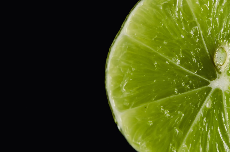 black background, purity, copy space, cross section, cut out, fruit, indoors, close-up, green, food, juicy, lemon, citric, single object, slice, no people
