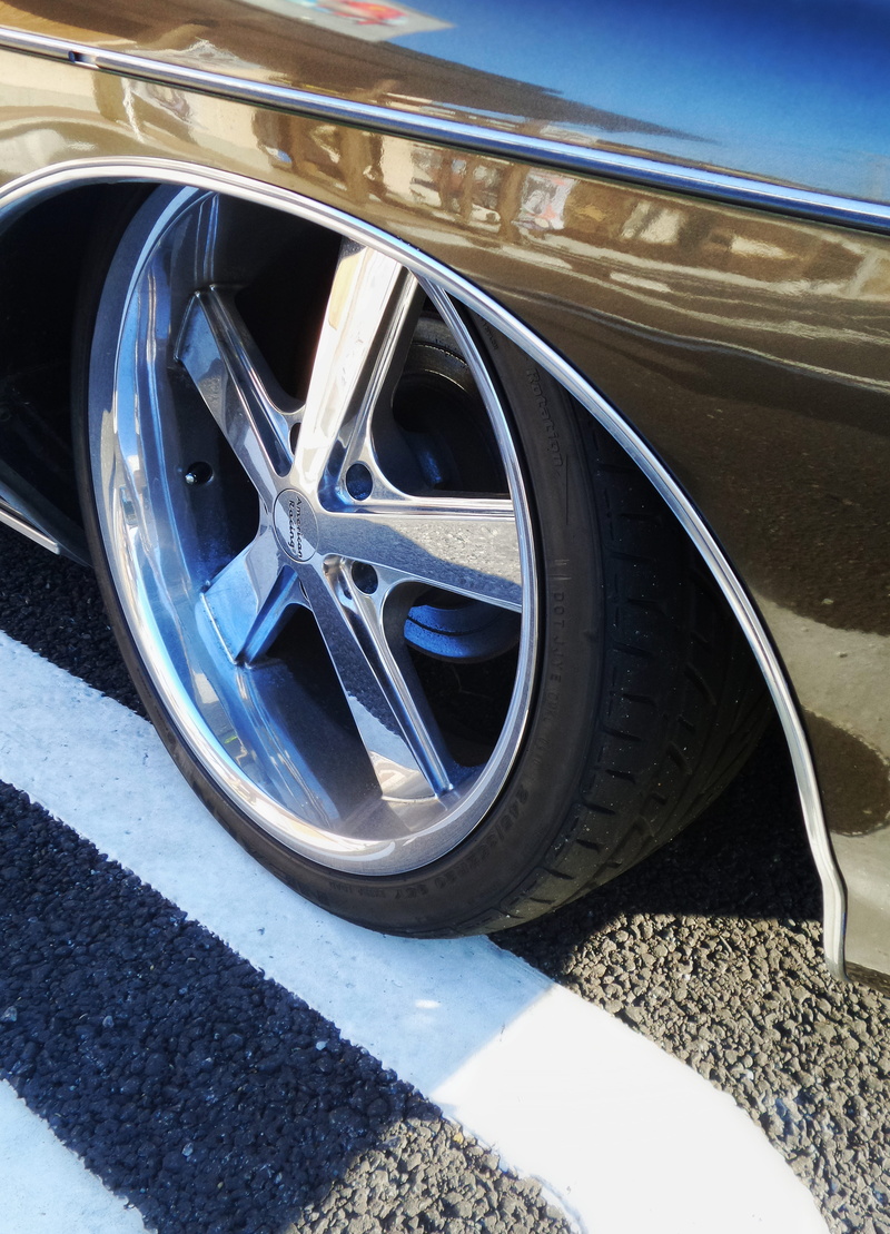spoke, stationary, wheel, reflection, sunlight, outdoors, nature, mode of transportation, chrome, city, travel, road, land vehicle, day, blue, luxury, motor vehicle