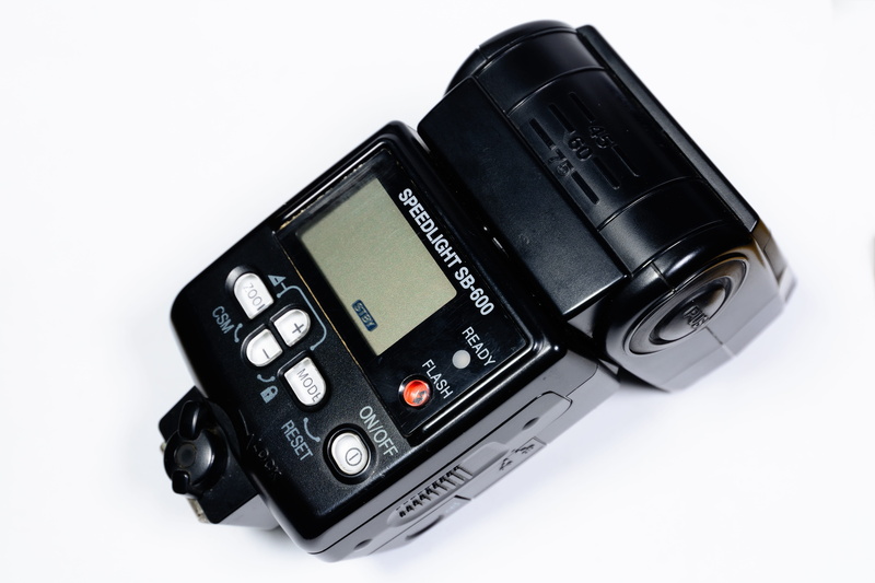 single object, indoors, nikon, digital camera, white background, studio shot, high angle view, modern, communication, camera, photographic equipment, close-up