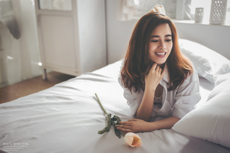 portrait, bedroom, home interior, textile, happiness, looking at camera, yellow roses, smiling, brunette, one person, hairstyle, looking away, lying on front