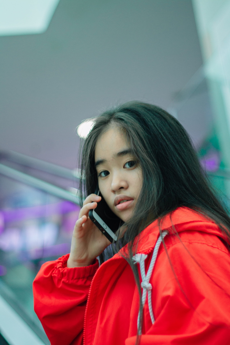 talking, indoors, brunette, hairstyle, close-up, calling, casual clothing, red jacket, pretty, front view, girl, smartphone, jacket, one person, leisure activity
