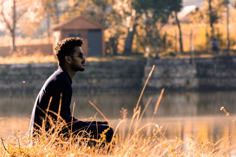 real people, plant, alone, grass, casual clothing, contemplation, one person, lifestyles, side view, thinking, idle, sunset, man, young adult, lake, outdoors