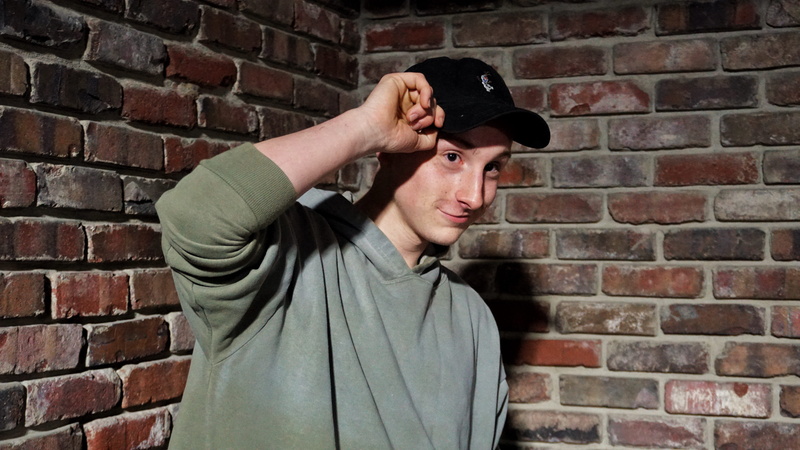 cap, fashion, clothing, 5K, front view, mouth open, lifestyles, cup, brick wall, united states, standing, skin, wall, apparel, face, one person, architecture