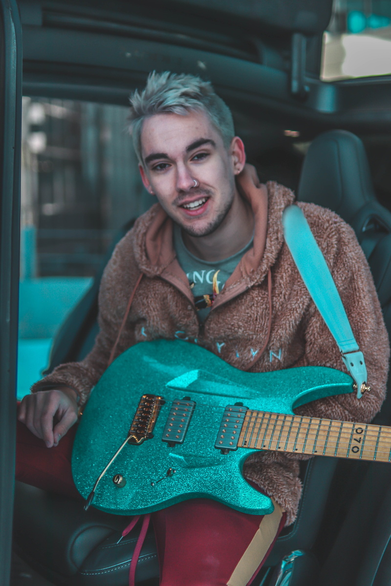 guitar, lute, person, teal, fleece, stratocaster, indoors, lifestyles, man, leisure activities, car wheel, wheel, geranium, sitting, bass guitar, skin
