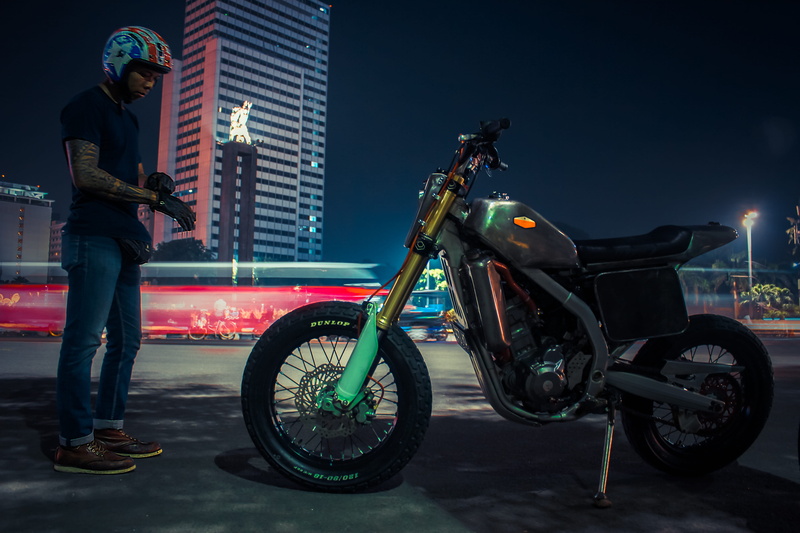 wheel, person, built structure, one person, casual clothing, spoke, architecture, outdoors, shoe, tire, guitar, helmet, office building exterior, real people
