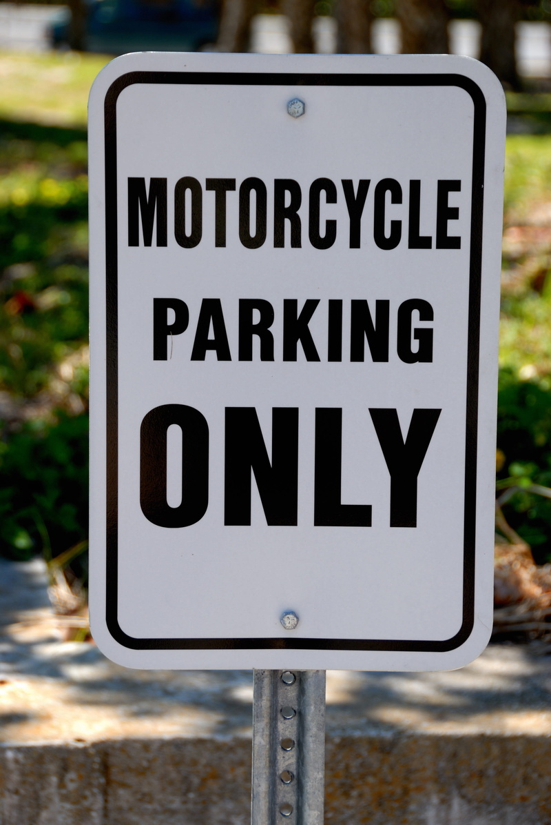 day, regulation, message, road sign, motorcycle parking, outdoors, street, city, vehicle, black color, road, white, text, attention, western script, guidance