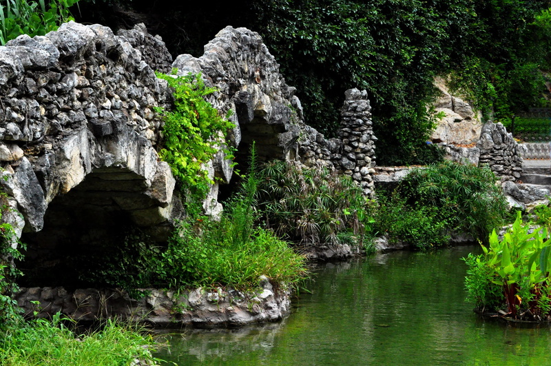 rock - Object, outdoors, famous Place, mountain, waterfront, old, growth, pond, tree, solid, green Color, history, cave, travel, vegetation, tranquility