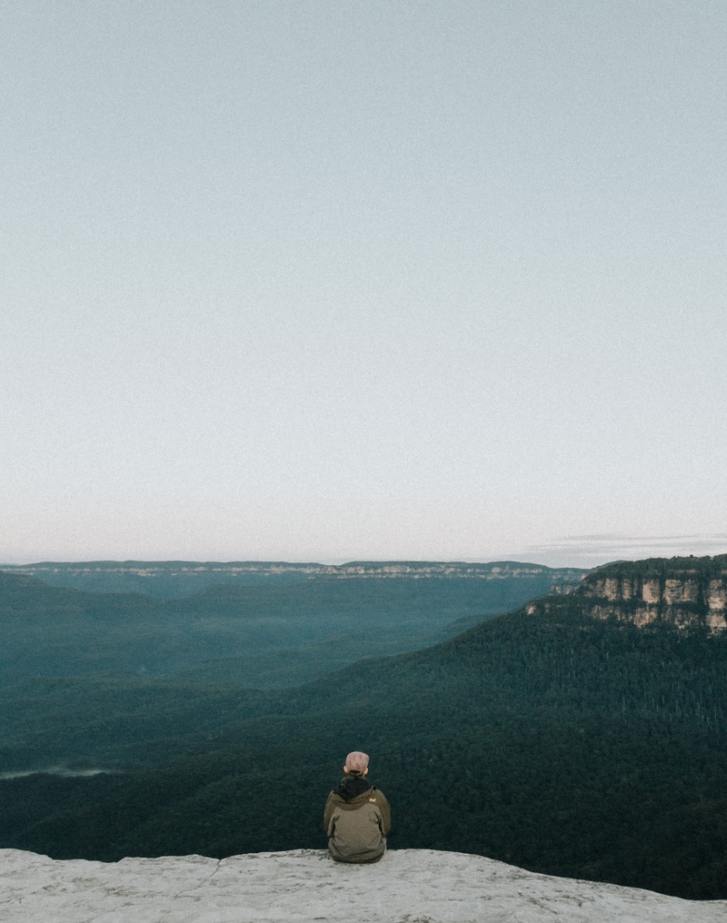 cliff, perosn, sit, color Image, water, ledge, clear sky, sitting, sea, leisure activity, Looking Out, rock, adults only, person, nature, non-urban scene