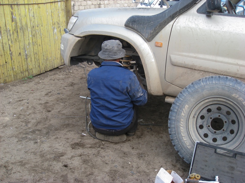 garage, men, full length, adult, mechanic, tire, males, occupation, transportation, mongolia, clothing, crouching, car, one person, car breakdown, rear view