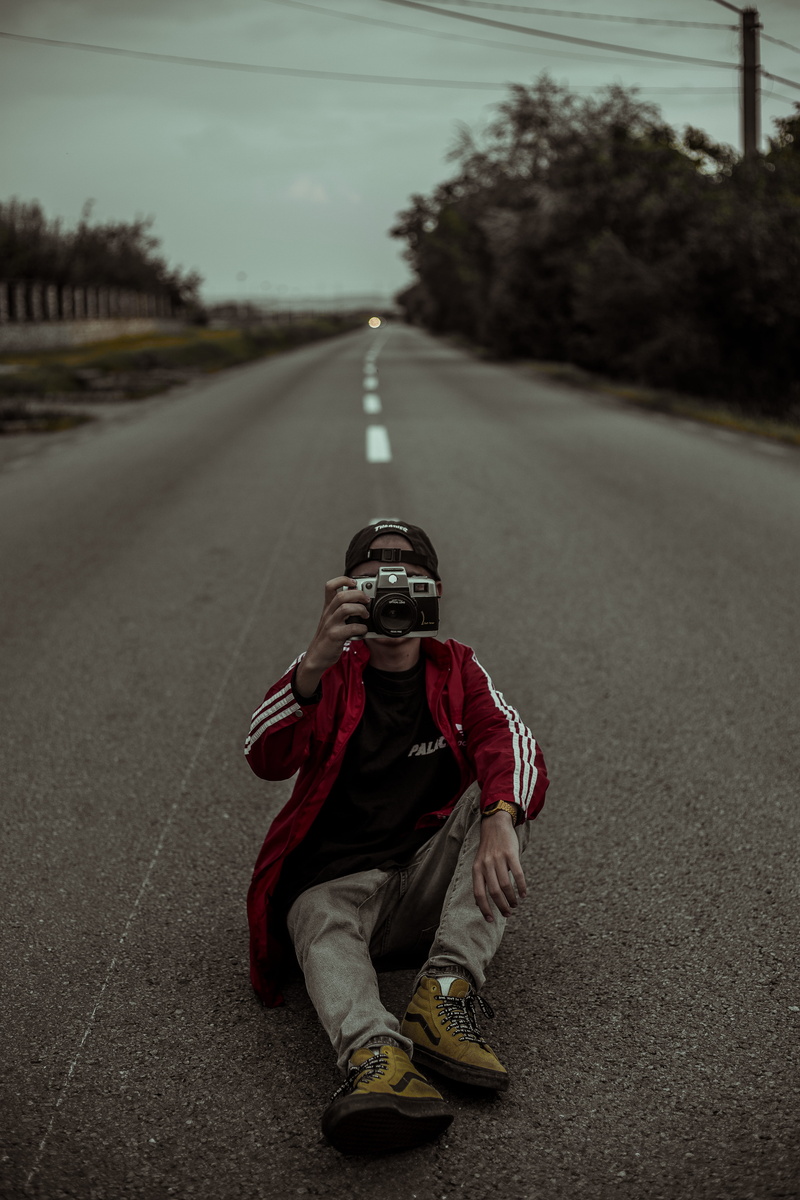 looking at camera, moody road, transportation, city, street, day, photo, lifestyles, human, footwear, clothing, electronics, diminishing perspective, photography