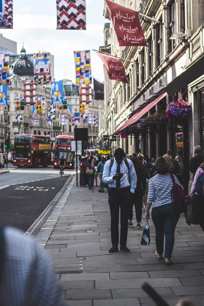 red bus, walking, flag, market, uk, sidewalk, street photography, group of people, england, men, women, lifestyles, architecture, people, mobile phone