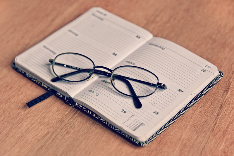 desk, communication, indoors, agenda, high angle view, schedule, deadline, open, organizer, book, eyeglasses, personal accessory, close-up, spectacles