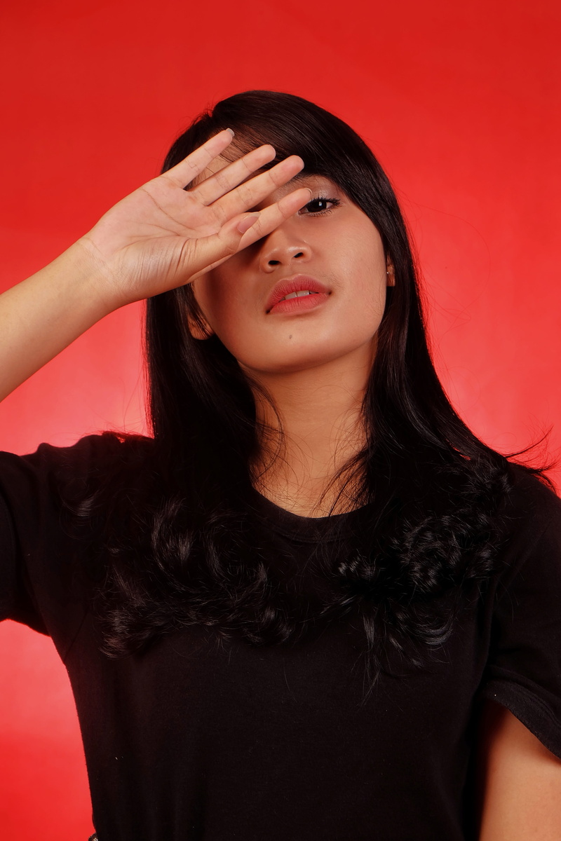 adult, portrait, young adult, body part, red background, one person, black hair, hairstyle, young women, studio shot, high light, indoors, women, casual clothing