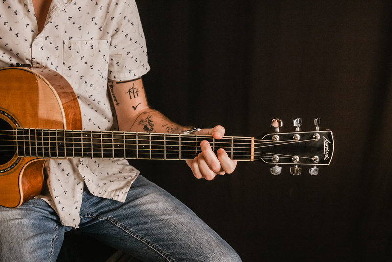 jeans, indoors, string instrument, bass guitar, musical instrument, adult, casual clothing, skin, girl, blonde, skill, black background, artist, human body part