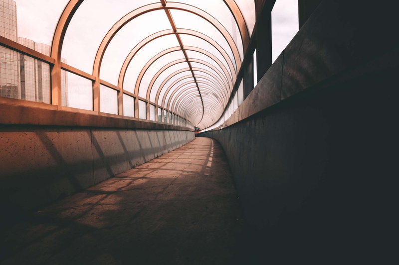 long, wall - building feature, direction, connection, passage, arch, travel, elevated walkway, light, passage way, indoors, the way forward, glass, footbridge