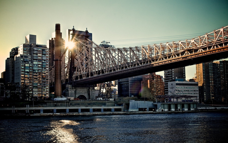 building, sunlight, architecture, bridge, office building exterior, travel destinations, waterfront, water, lens flare, built structure, New York City