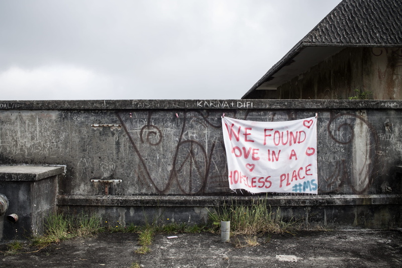 hanging, text, no people, run-down, building, building exterior, ruin, sky, graffiti, built structure, day, cloud - sky, communication, red, grey, writing