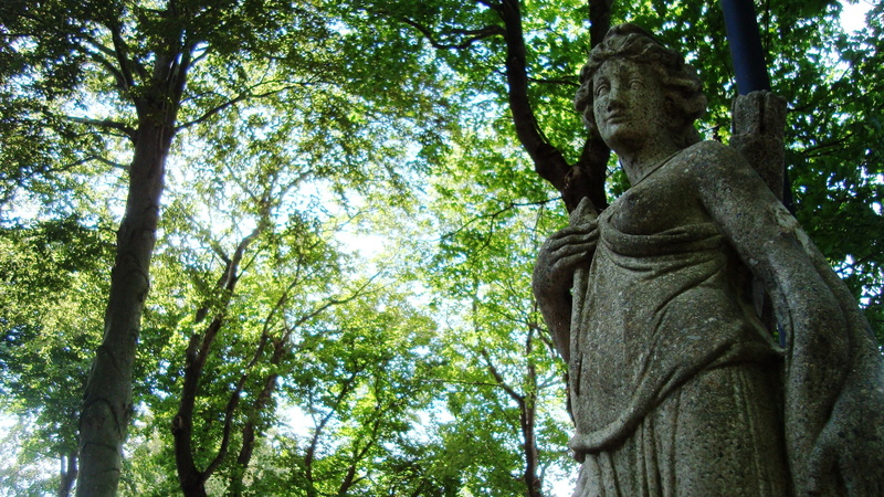 low angle view, statue, human representation, no people, archery, sculpture, archer, tree, outdoors, belief, nature, craft, tree trunk, goddess, male likeness