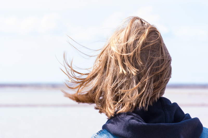 infinite, portrait, hair flying, wide, focus on foreground, facing, blonde, long hair, young woman, warm clothing, loneliness, outdoors, haired, tousled