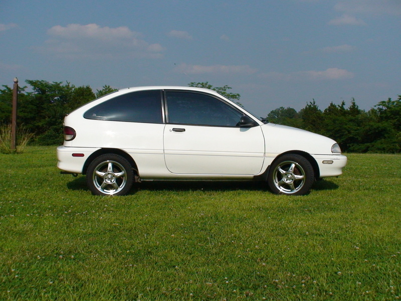 tree, green color, white color, Wheels, motor vehicle, outdoors, white, field, Aspire, Custom, side view, Ford, sky, land vehicle, stationary, no people