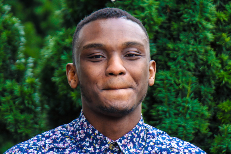 dressed, focus on foreground, eyes, young men, plant, one person, headshot, ebony, ear, tree, nose, yellow, flower, looking at camera, near, forest, portrait