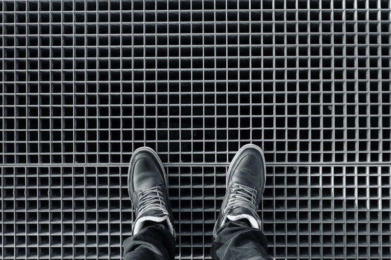 lifestyles, one person, pattern, tile, standing, human foot, jeans, body part, leisure activity, shoe, pair, boots, black, shoes, men, high angle view