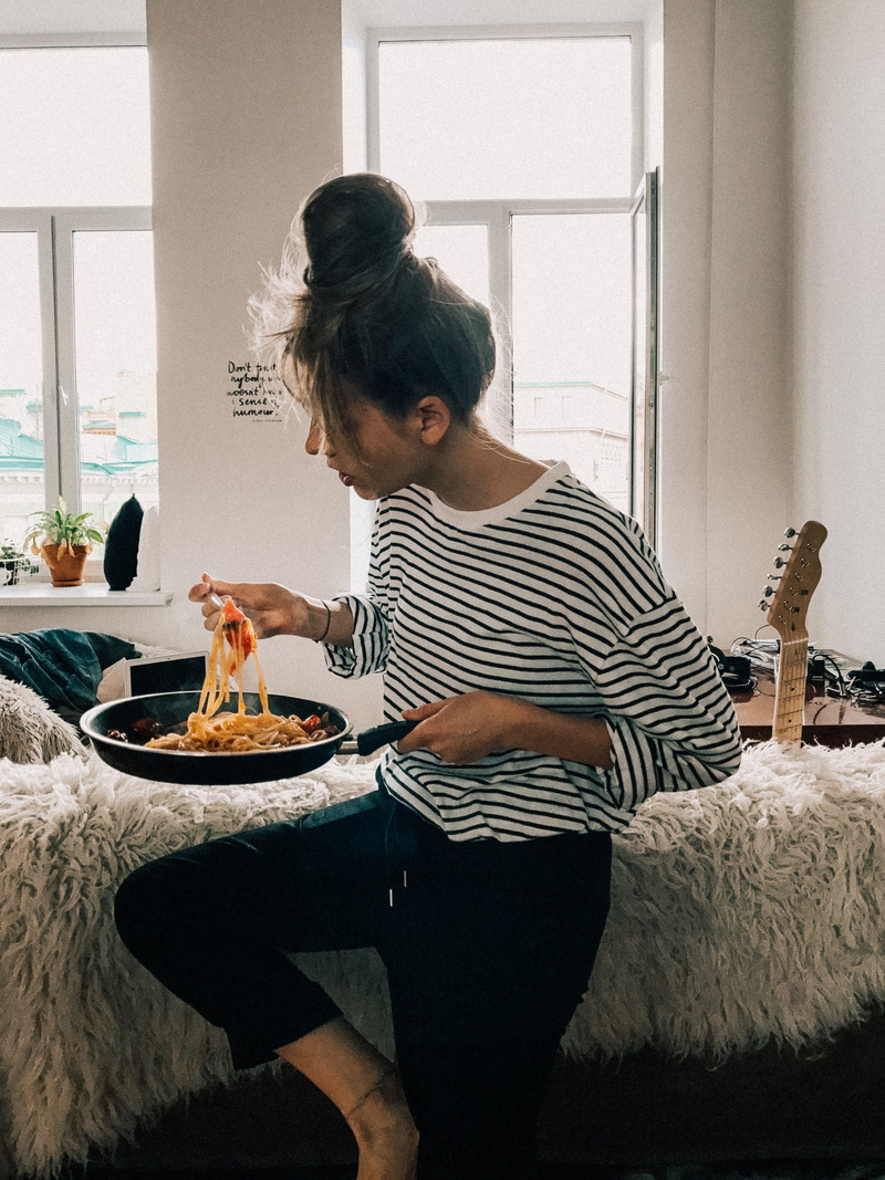 white, shirt, room, eating, food and drink, indoors, pot, one person, leisure activity, windows, woman, domestic room, black, lifestyles, sitting, three quarter length