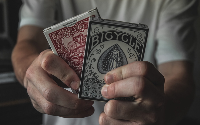 two, paper currency, indoors, holding, playing, human finger, playing cards, finance, boxes, body part, real people, human body part, cards, person, one person