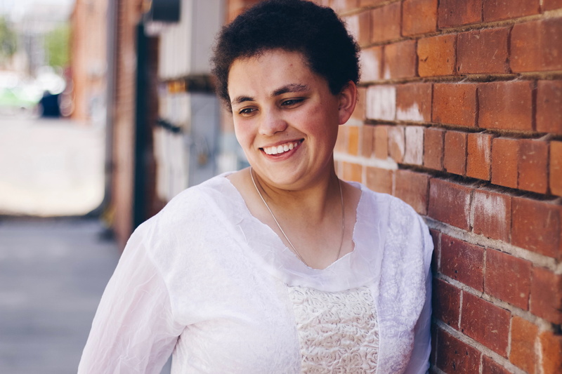 front view, outdoors, smiling, people, one person, woman, happiness, portrait, brick wall, denver, person, architecture, short hair, leaning, happy, wall