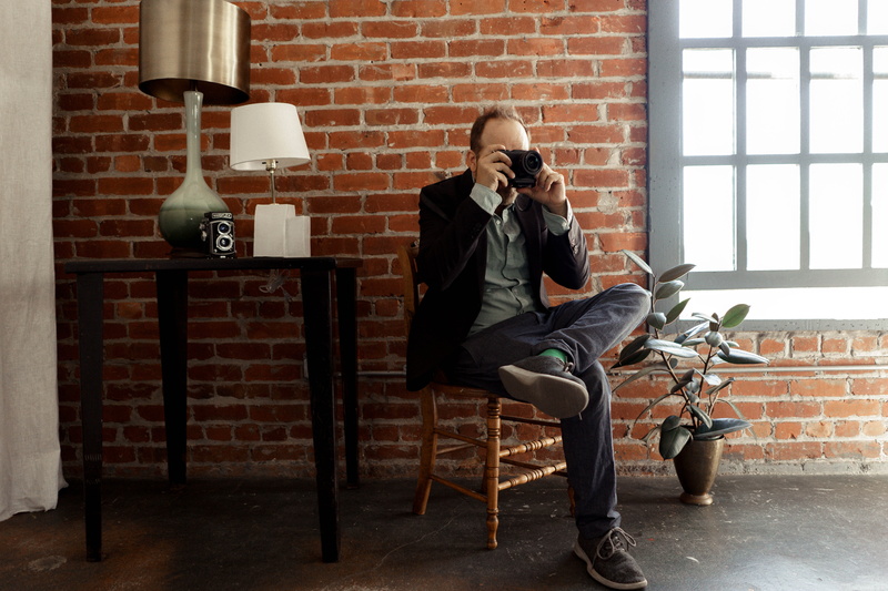 united states, wall, communication, studio, man, sitting, photographer, brick, leisure activity, wall - building feature, real people, chair, young adult