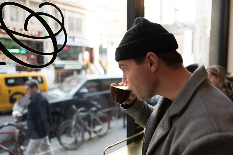sip, headshot, side view, warm clothing, coffee, holding, leisure activity, coffee shop, indoors, one person, man, maker, window, new york city, create